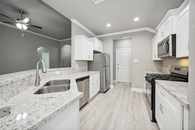 kitchen with appliances with stainless steel finishes, white cabinets, a sink, and light stone countertops