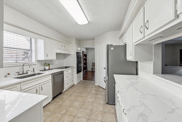 kitchen featuring light tile patterned floors, white cabinets, a sink, a textured ceiling, and black appliances