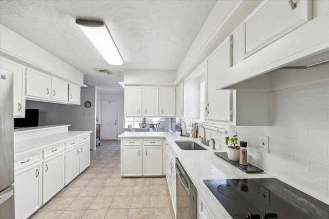 kitchen with white cabinets, a peninsula, black electric stovetop, light countertops, and a sink