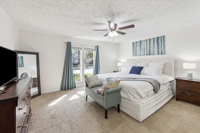 bedroom featuring ceiling fan, baseboards, a textured ceiling, and light colored carpet