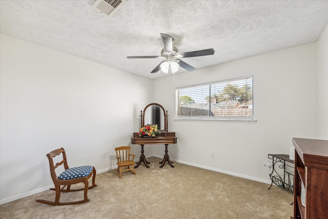 sitting room with light carpet, baseboards, visible vents, a ceiling fan, and a textured ceiling