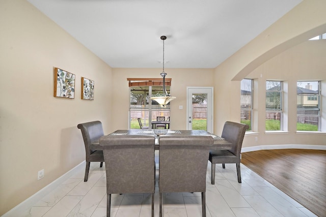 dining space with baseboards and arched walkways