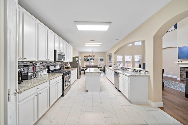 kitchen with pendant lighting, appliances with stainless steel finishes, white cabinets, and a center island