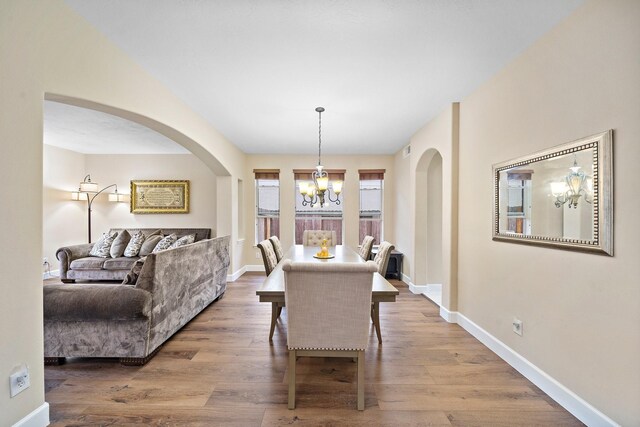 dining room with a chandelier, baseboards, and wood finished floors