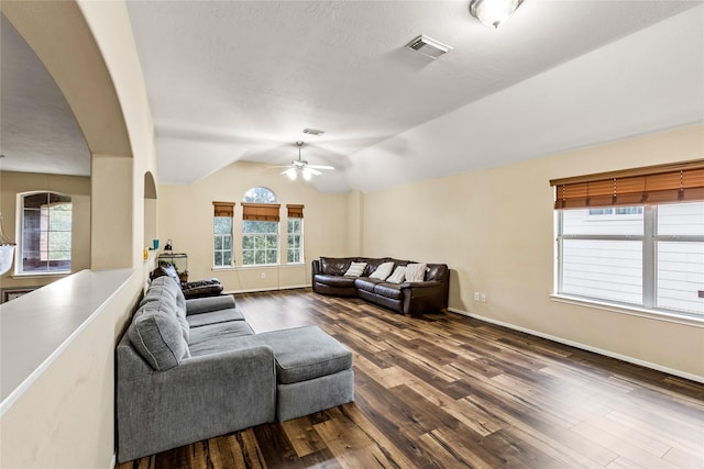 living room with baseboards, visible vents, lofted ceiling, ceiling fan, and dark wood-style flooring