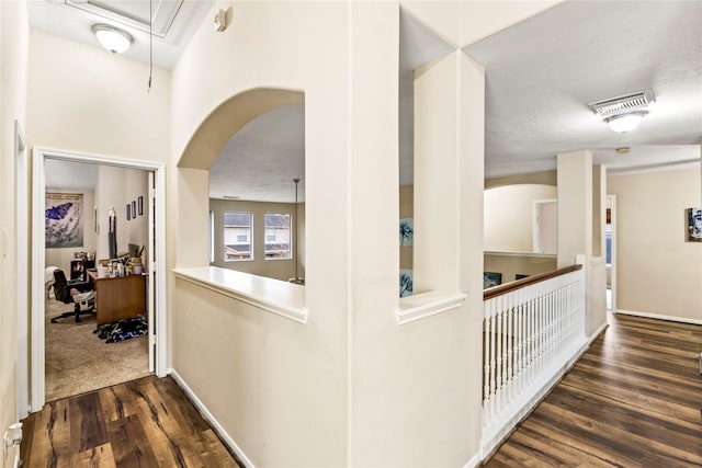 hall featuring attic access, visible vents, arched walkways, and dark wood-type flooring