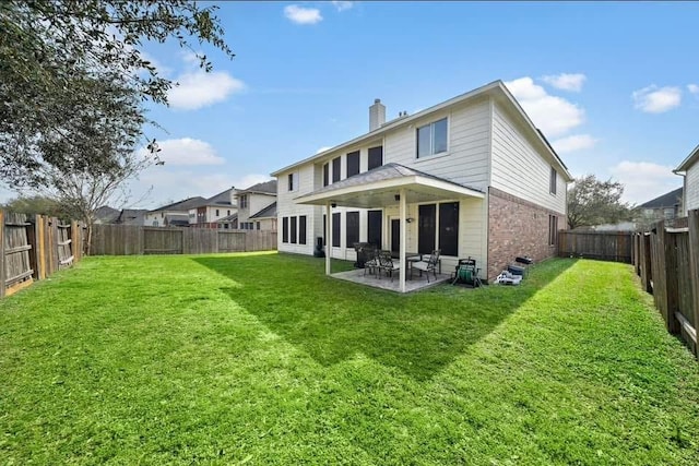 rear view of property featuring a patio, a fenced backyard, a chimney, a yard, and brick siding