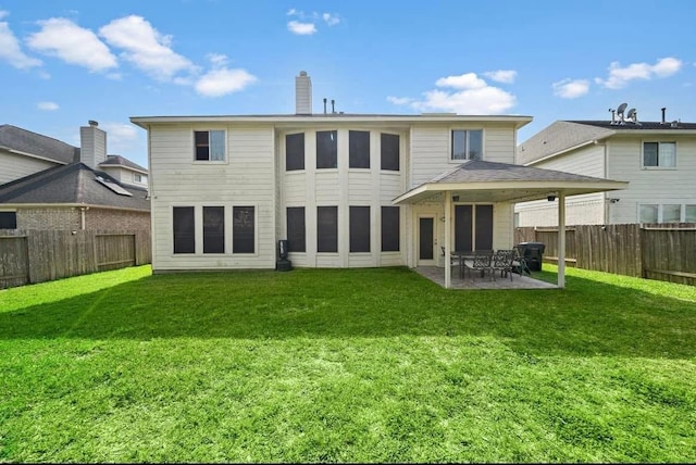 rear view of property featuring a yard, a chimney, a patio, and a fenced backyard