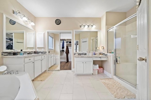 full bathroom featuring a walk in closet, a garden tub, a shower stall, and vanity