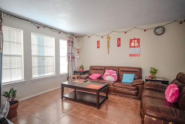 living room with light tile patterned floors, baseboards, and a textured ceiling