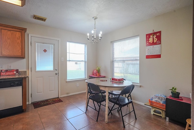 dining space with a notable chandelier, a healthy amount of sunlight, visible vents, and a textured ceiling