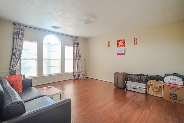 living area featuring visible vents, baseboards, a textured ceiling, and wood finished floors