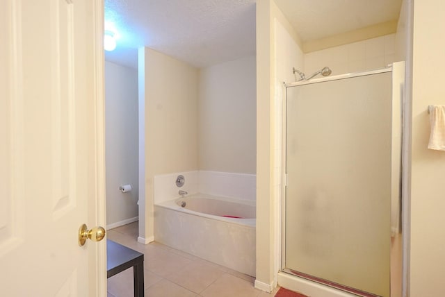 full bathroom featuring tile patterned floors, a garden tub, a stall shower, a textured ceiling, and baseboards