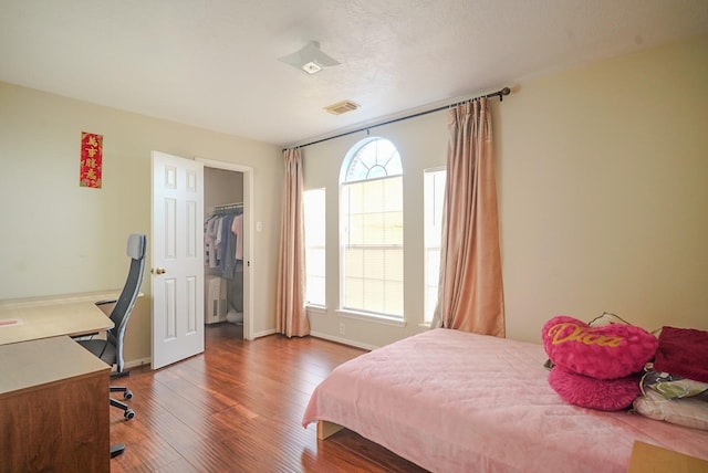 bedroom with visible vents, multiple windows, baseboards, and wood finished floors