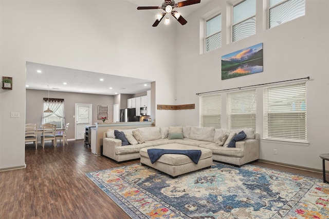 living area with baseboards, ceiling fan, wood finished floors, a high ceiling, and recessed lighting