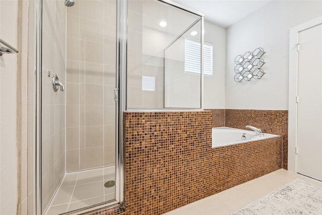 bathroom featuring a garden tub, a shower stall, tile patterned flooring, and tile walls