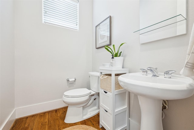 half bathroom featuring toilet, baseboards, and wood finished floors