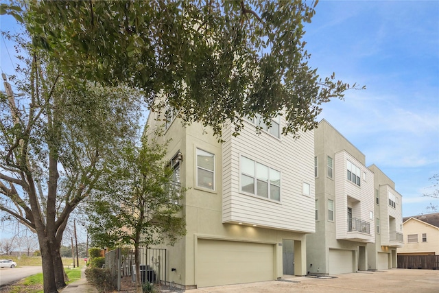 townhome / multi-family property featuring a garage, driveway, central air condition unit, and stucco siding