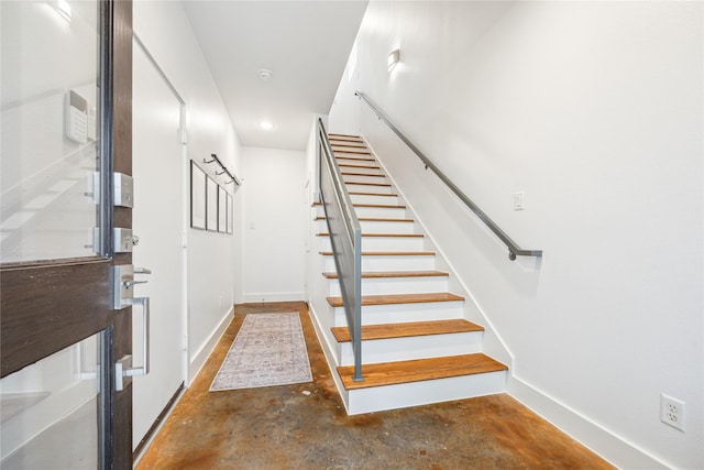 stairs with unfinished concrete flooring and baseboards