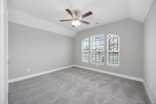 spare room featuring baseboards, visible vents, ceiling fan, carpet, and vaulted ceiling