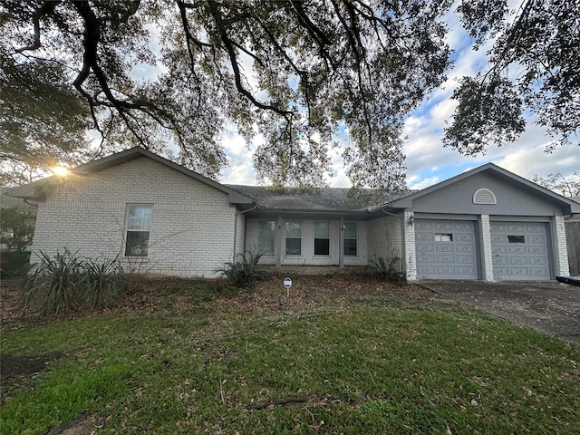 single story home featuring a garage, brick siding, aphalt driveway, and a front yard