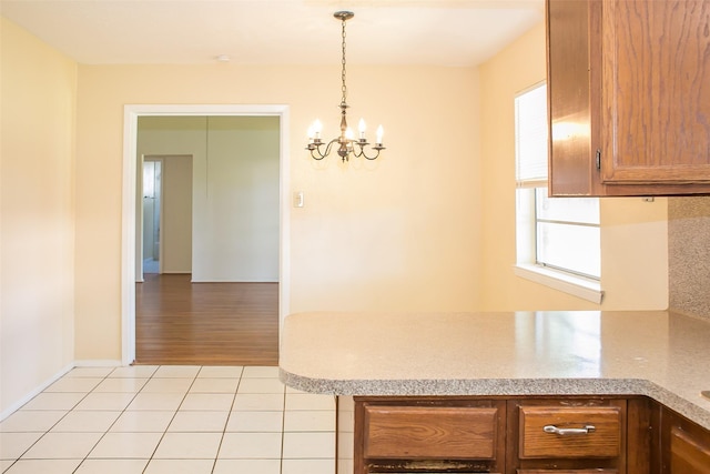 kitchen featuring light tile patterned floors, a chandelier, light countertops, hanging light fixtures, and brown cabinets