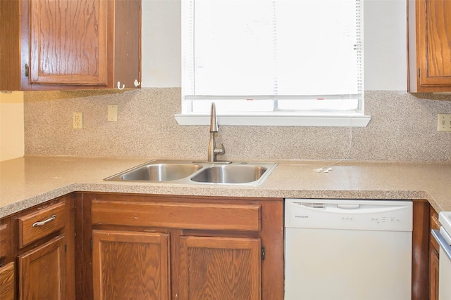 kitchen featuring light countertops, backsplash, white dishwasher, and a sink