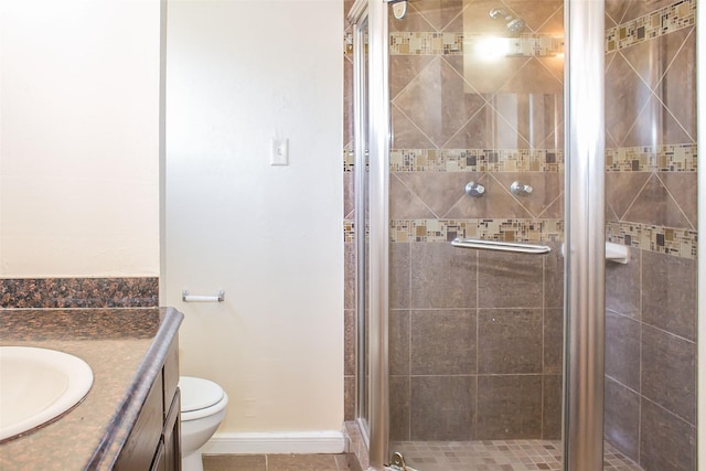 bathroom with toilet, a shower stall, baseboards, and vanity