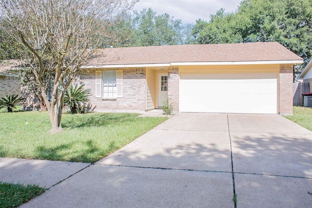 view of front of house with a front yard, brick siding, driveway, and an attached garage