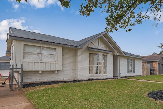 ranch-style home featuring brick siding, a front lawn, and roof with shingles