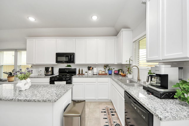 kitchen with tasteful backsplash, light stone counters, black appliances, white cabinetry, and a sink