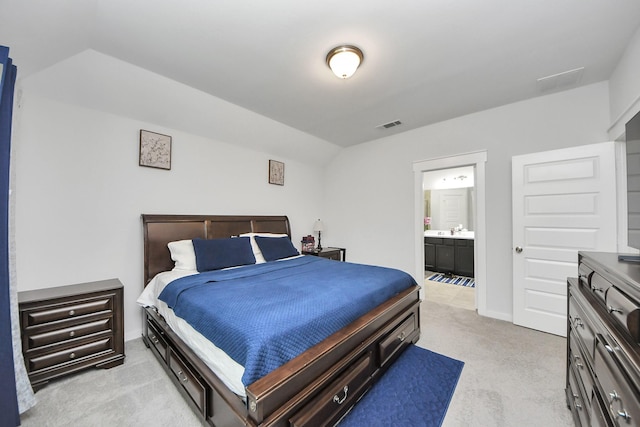 bedroom with lofted ceiling, ensuite bathroom, visible vents, and light colored carpet