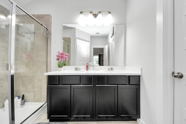 full bathroom featuring double vanity, a shower stall, and a sink