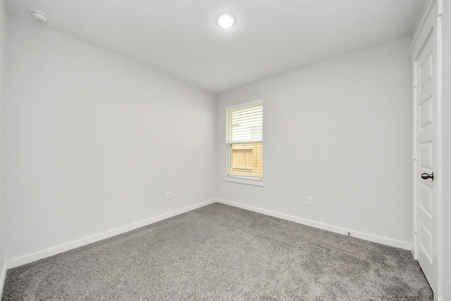 spare room with baseboards and carpet flooring