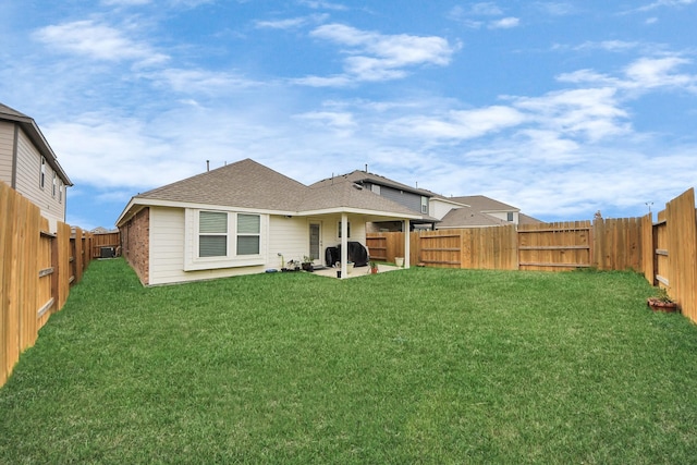 back of house featuring a fenced backyard, a shingled roof, a lawn, and a patio