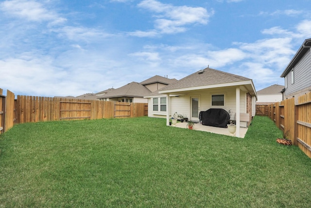 rear view of property featuring a patio area, a fenced backyard, a shingled roof, and a lawn