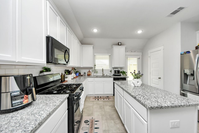 kitchen featuring visible vents, a center island, black appliances, white cabinetry, and a sink