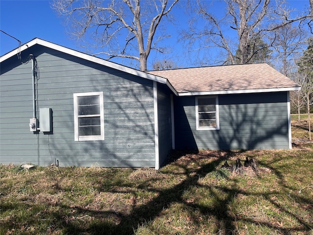 view of side of property with a yard and a shingled roof