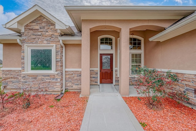 doorway to property with stone siding and stucco siding