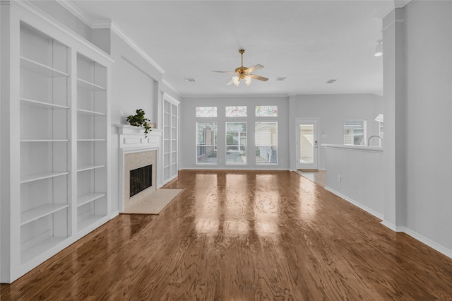 unfurnished living room featuring a premium fireplace, ornamental molding, a ceiling fan, wood finished floors, and baseboards