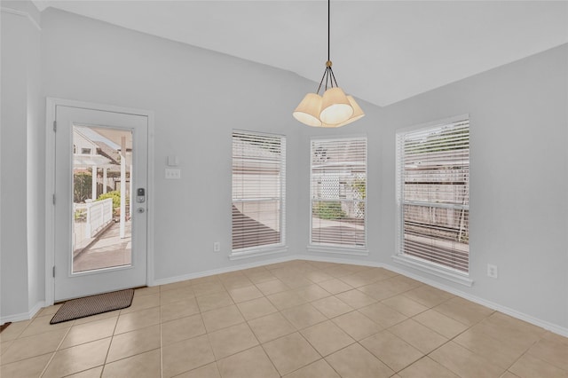 unfurnished dining area featuring lofted ceiling, baseboards, and light tile patterned floors