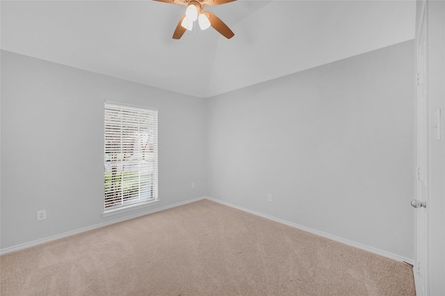 carpeted spare room with vaulted ceiling, a ceiling fan, and baseboards