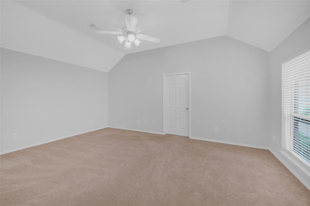 additional living space featuring light colored carpet, vaulted ceiling, baseboards, and ceiling fan