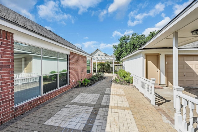 view of patio featuring a garage, fence, and a pergola