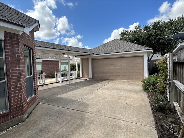 view of front of house featuring roof with shingles, fence, driveway, and brick siding