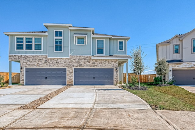 view of front of property featuring concrete driveway, an attached garage, board and batten siding, fence, and stone siding