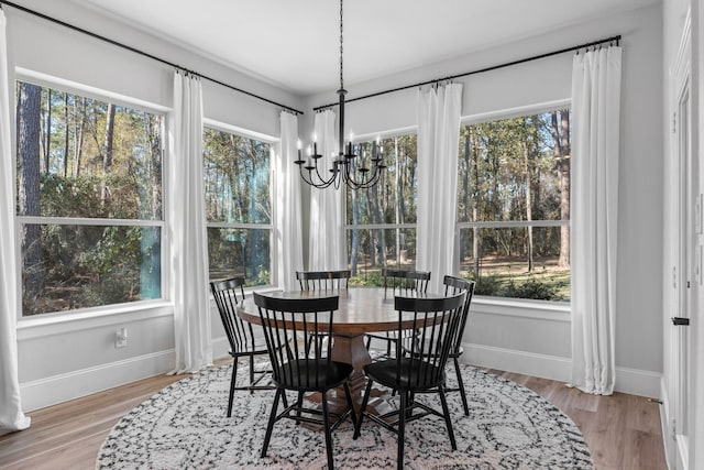 dining space featuring light wood-type flooring, baseboards, and an inviting chandelier