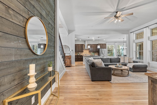 living room with recessed lighting, light wood-style flooring, stairs, and ceiling fan with notable chandelier