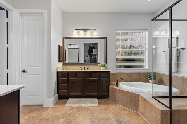 full bathroom with stone finish floor, vanity, and a bath