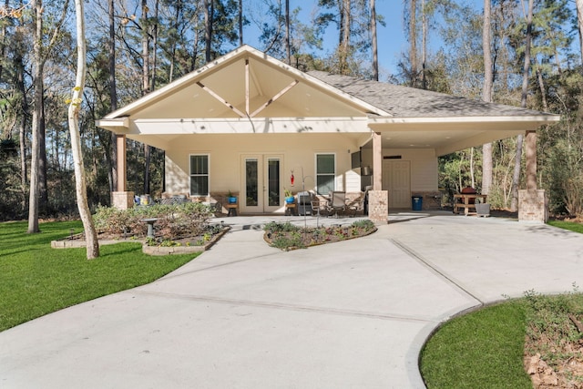 view of front of home featuring concrete driveway, french doors, a front lawn, and an attached carport